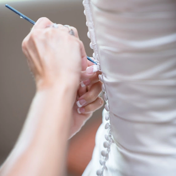 Close-up of hands pinning wedding dress for expert alterations in Tucson and Phoenix