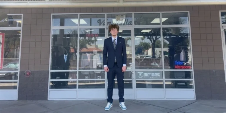 A happy customer wearing a fitted navy blue graduation suit outside our Phoenix alterations shop front.