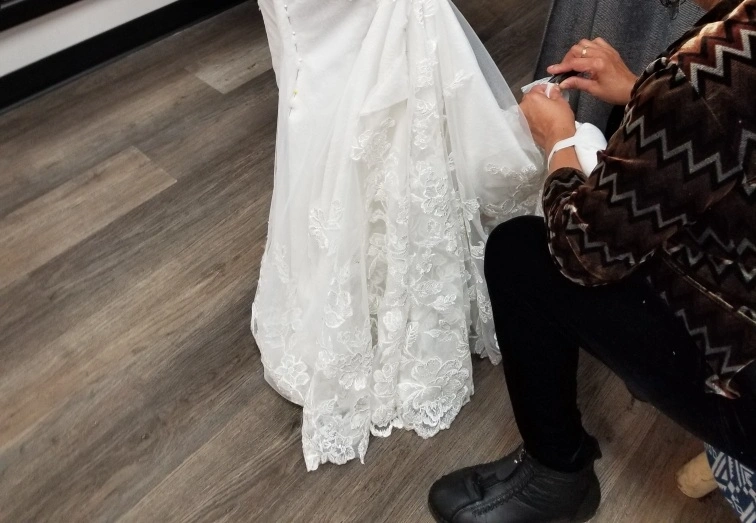 Precision Alterations in Phoenix pinning the back hem of a dress during a fitting appointment for bridesmaid dress alterations Phoenix.